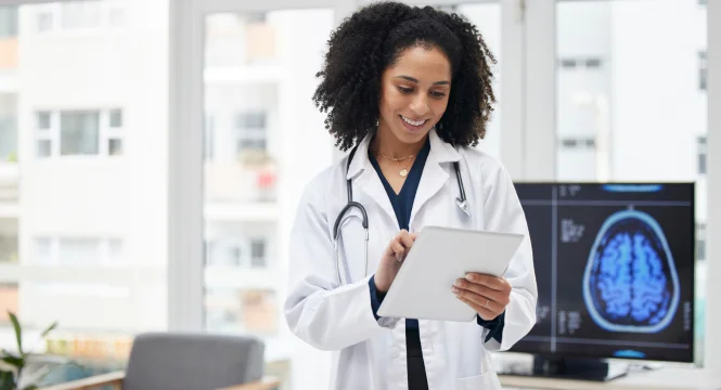 Smiling female doctor using a tablet in a modern medical office.